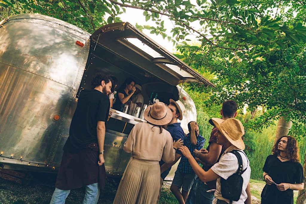 Vintage trailer adibito a food truck circondato da persone intente ad ordinare da mangiare e da bere