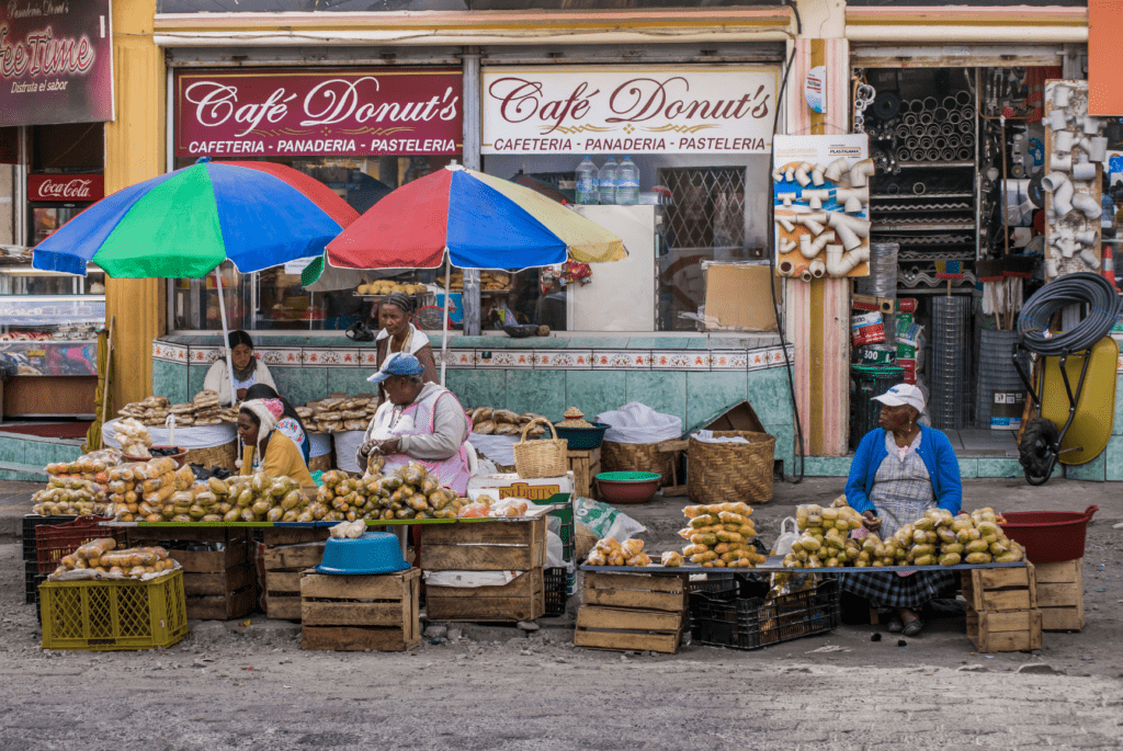 Mercato tradizione che raffigura venditori ambulanti seduti di fronte ai loro banchetti di frutta, cibo e oggettistica