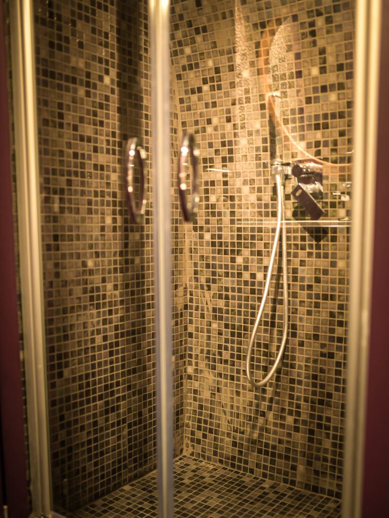 Dettaglio della doccia piastrellata a mano con mosaico