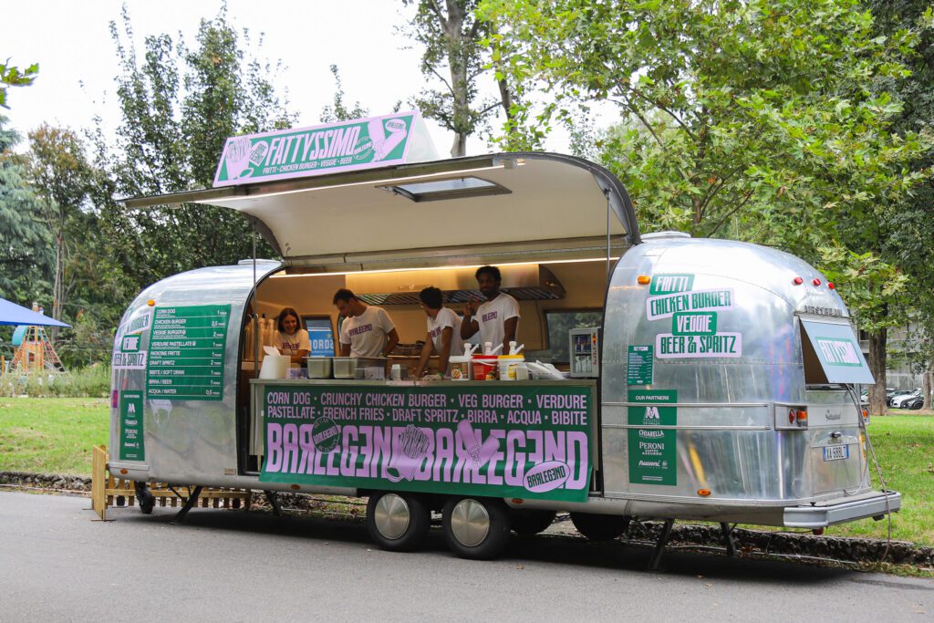 Airstream food truck nel parco di Monza, circondato da alberi 